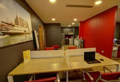 Shared workspace with laptop on a light wood desk beside a vibrant red feature wall.