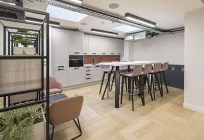 Modern communal kitchen and dining area with light wood floors and a high breakfast bar.