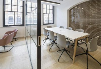 Professional meeting room with a white table, grey chairs, and a glass partition wall.