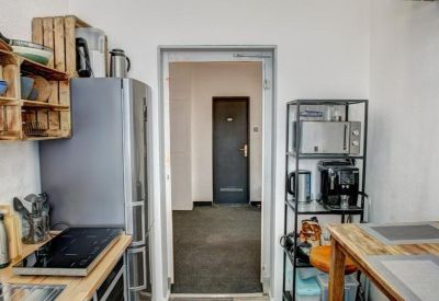 Compact kitchen area with a refrigerator, wooden shelving, and a stove.