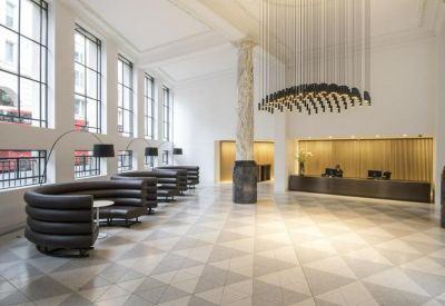 Grand lobby featuring a marble column, geometric floor tiles, and a sculptural black chandelier.