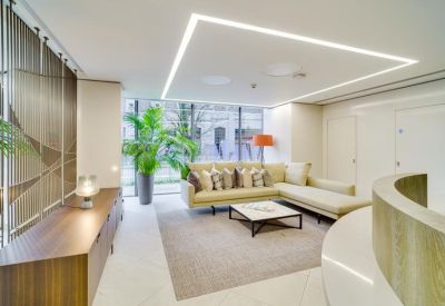 Bright lounge area with an L-shaped sofa, marble coffee table, and large potted plant.