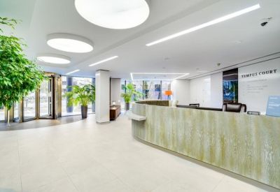 Reception area with a light wood curved desk and sleek linear ceiling lights.