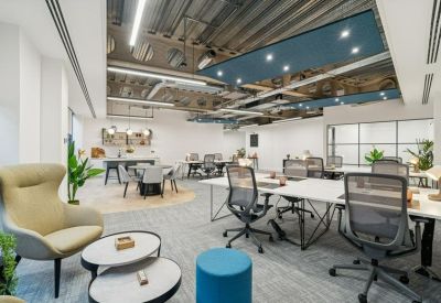 Spacious open-plan office with exposed industrial ceilings and a mix of seating areas.