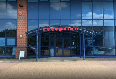 Front entrance with blue-framed glass doors and a red reception sign.