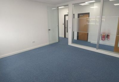 Empty office space with blue carpeting and glass partition walls.