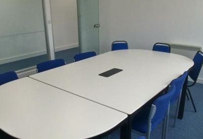 Meeting room featuring a large oval table and blue upholstered chairs.