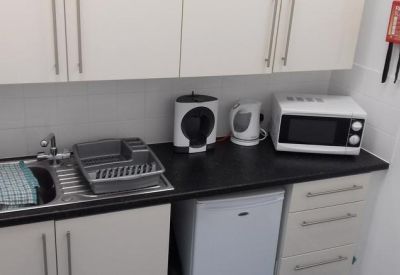 Compact kitchenette with coffee machine, microwave, and mini-fridge.