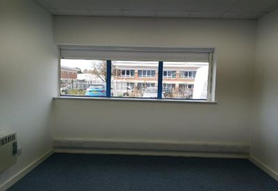 Empty private office with a wide window and blue carpeting.