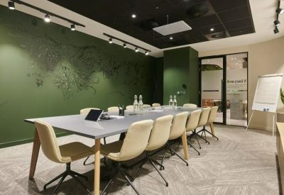 Large conference room with a long grey table, cream chairs, and a world map graphic on a green feature wall.