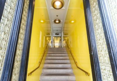 Bright yellow entrance corridor with a central staircase and decorative glass side panels.