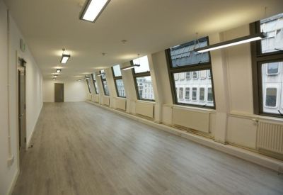 Spacious open-plan office area with light wood flooring and slanted windows.