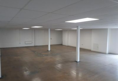 Spacious open-plan office area with white pillars and a tiled ceiling.