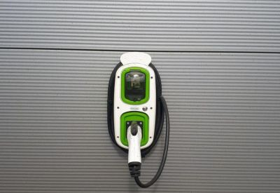Electric vehicle charging point mounted on a grey corrugated metal wall.