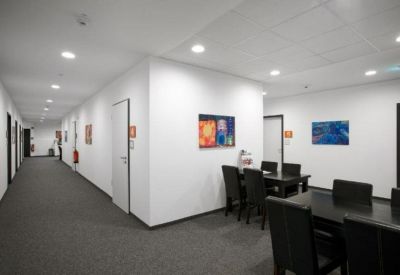Bright communal dining area with dark wooden tables and colourful abstract wall art.