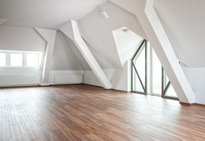 Spacious attic office area with warm hardwood floors and unique architectural white support beams.