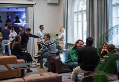 Spacious lounge area with people networking on brown leather sofas and chairs.