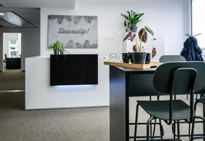 Bright reception area with white desk, wall art, and indoor plants.