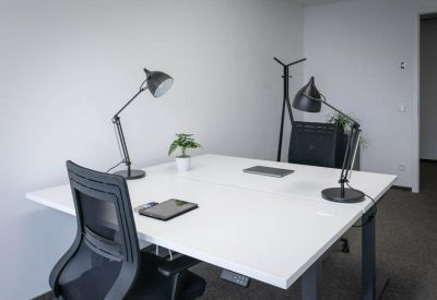 Private two-person office with white desks and black task lamps.