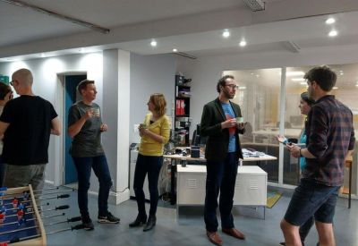 Casual breakout space with people chatting near a foosball table.