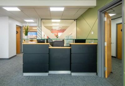 Sleek black reception desk with glass partitions and an adjacent green accent wall.