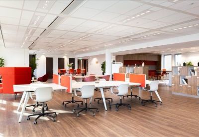 Spacious coworking area with vibrant orange room dividers and wooden flooring.