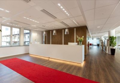 Sleek white reception desk with a vibrant red runner rug and wooden feature wall.