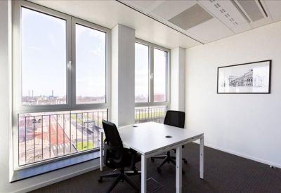 Bright corner office suite with two white desks and large windows overlooking the city.