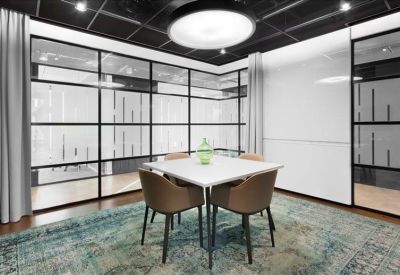 Four-person meeting room with a white square table and a plush patterned rug.