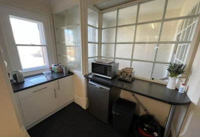 Communal kitchenette equipped with a microwave, mini-fridge, and black countertop.