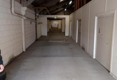 Industrial-style internal corridor with concrete flooring and white partitioned walls.