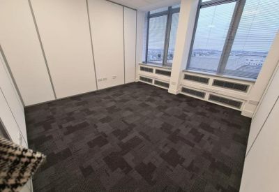 Corner office suite with dark patterned carpeting and large windows overlooking the city.