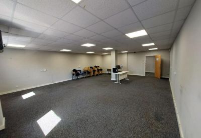 Expansive open-plan office area with neutral walls, grey carpeting, and recessed ceiling lighting.