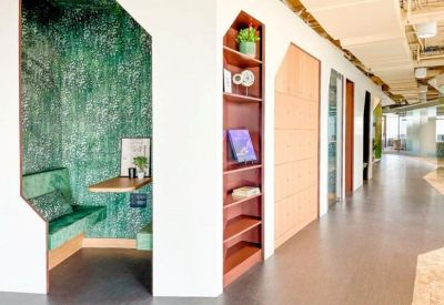 Private green-walled workspace nook alongside a wooden bookshelf and corridor.