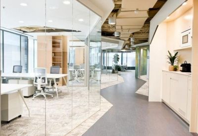 Sleek office hallway with glass-walled meeting rooms and a refreshment station.