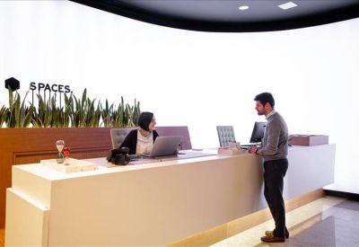 Bright reception area with a long white desk and branded signage against a glowing wall.