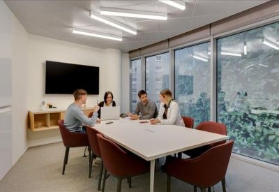 Professional meeting room with a large white table, red chairs, and wall-mounted screen.