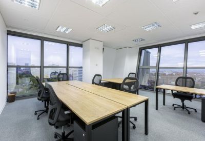 Bright office space with large windows and wooden workstations.