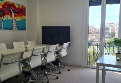 Conference room featuring a long white table, ergonomic chairs, and vibrant wall art.