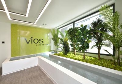 Bright reception lobby featuring a brand wall with green accents and indoor tropical plants.