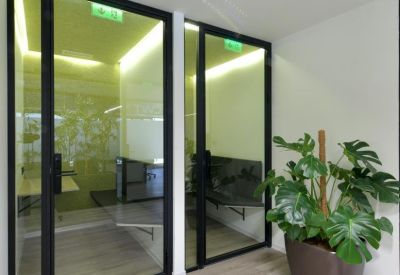 Minimalist hallway featuring private glass-walled phone booths and a potted plant.