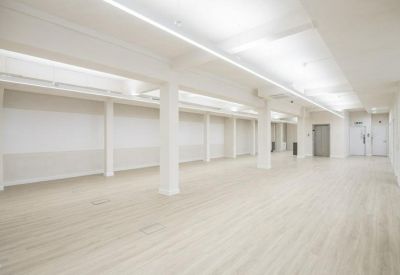 Bright, empty office suite with white columns and long overhead strip lighting.