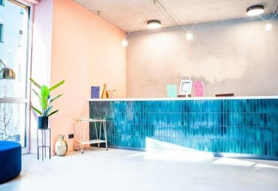 Bright reception desk with vibrant blue tiled facade and warm pink walls.