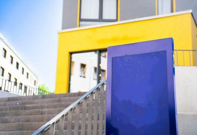 Exterior entrance at The Base Berlin One featuring yellow walls and a blue sign.