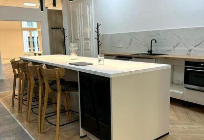 Communal kitchen area with a sleek white island and bar stools.