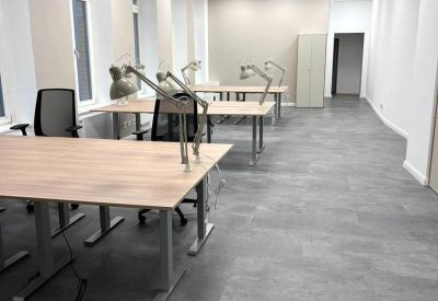 Open-plan office with multiple workstations and bright lighting.