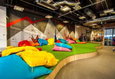 Colorful communal breakout area with bean bags, artificial turf, and hanging chairs.