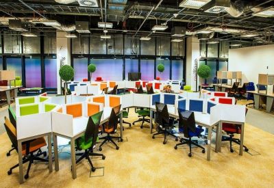 Modern open-plan workspace with colorful partitioned desks and ergonomic chairs.
