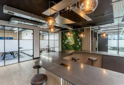 Breakout area with a curved wooden bar, designer pendant lights, and a lush green plant wall.