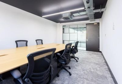 Professional meeting room with a long light-wood table and black mesh chairs.